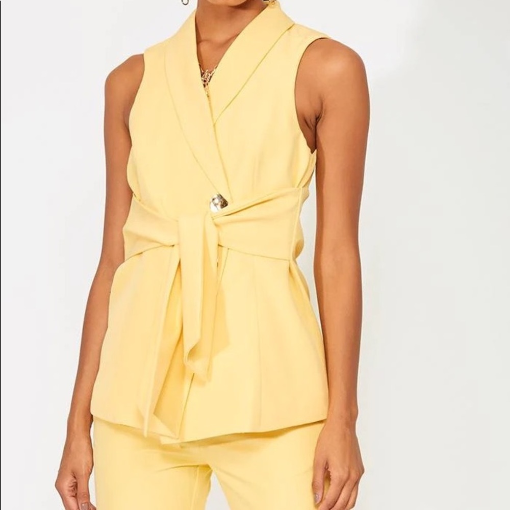 Pale yellow sleeveless tie-waist blazer.